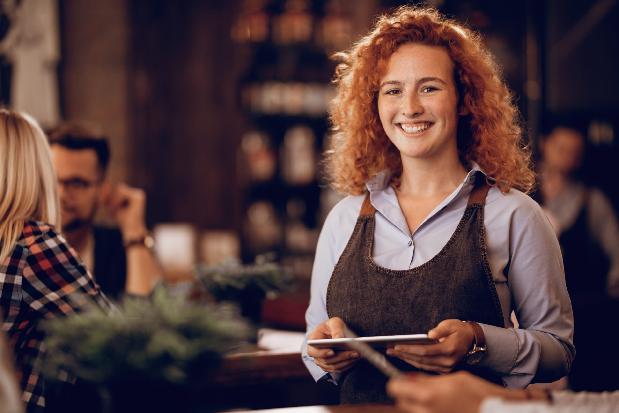 Portrait of young happy waitress with digital tablet in a bar
