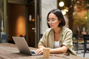 young-woman-working-cafe-using-laptop-drinking-coffee-asian-girl-student-with-computer-stud (1)