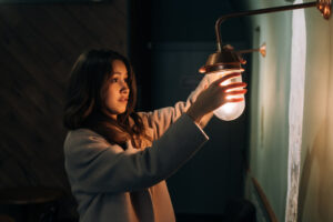 young-beautiful-woman-holds-her-hand-small-wall-lamp